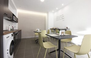 A modern kitchen with a washing machine, a sink, and a countertop. There are four chairs and a table with a small potted plant. - 3 bedroom nice apartment in Oliveto Citra (Oliveto Citra)