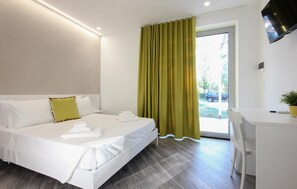 Une chambre d’hôtel avec un lit, un bureau, une télévision et une fenêtre avec des rideaux.