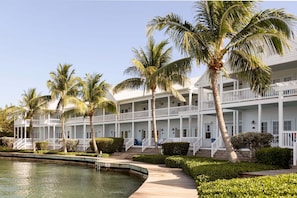 A multi-story hotel with balconies, a swimming pool, and palm trees.
