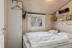 Ein Schlafzimmer mit einem Bett, einem Fenster und einer Holzbalkendecke.