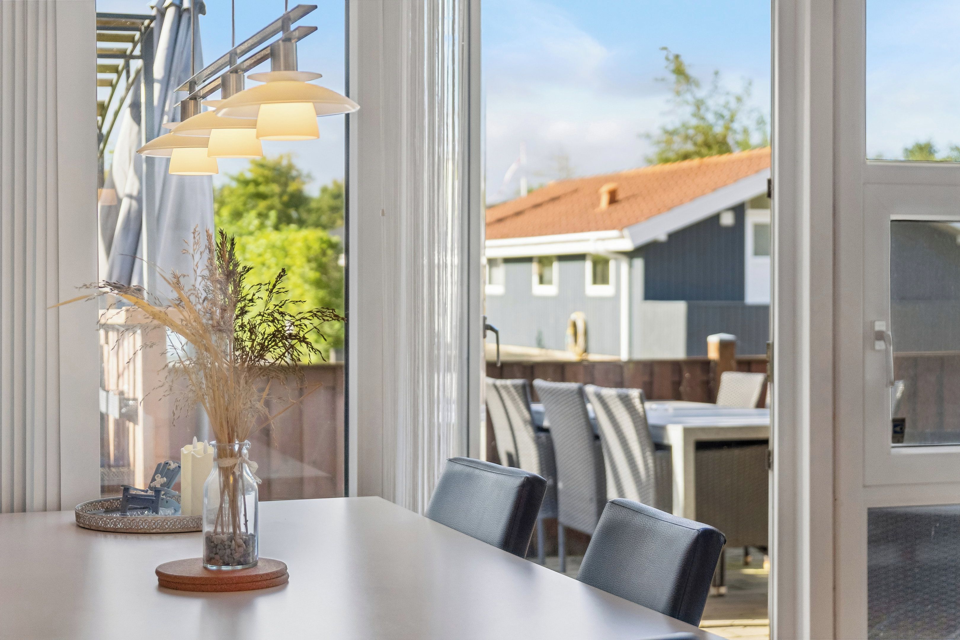 An outdoor dining area with a table, chairs, and a decorative vase with dried plants.