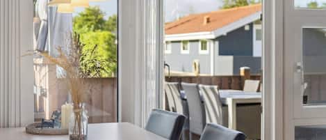 An outdoor dining area with a table, chairs, and a decorative vase with dried plants.