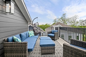 A covered outdoor seating area with wicker furniture and a patterned floor.