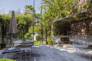 A patio with a stone table and chairs, surrounded by greenery and a stone wall. - CASA ALIZ (San Miguel de Allende)