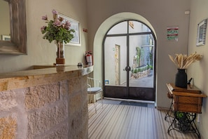 A reception area with a stone counter, a vase of flowers, a chair, and a door leading outside. - CASA ALIZ (San Miguel de Allende)