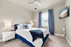 Un dormitorio con cama, mesita de noche, lámpara y ventilador de techo.