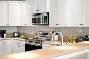 Una cocina moderna con muebles blancos, electrodomésticos de acero inoxidable y encimera de granito.