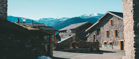 A stone building with a clock, a stone archway, and a mountain backdrop.