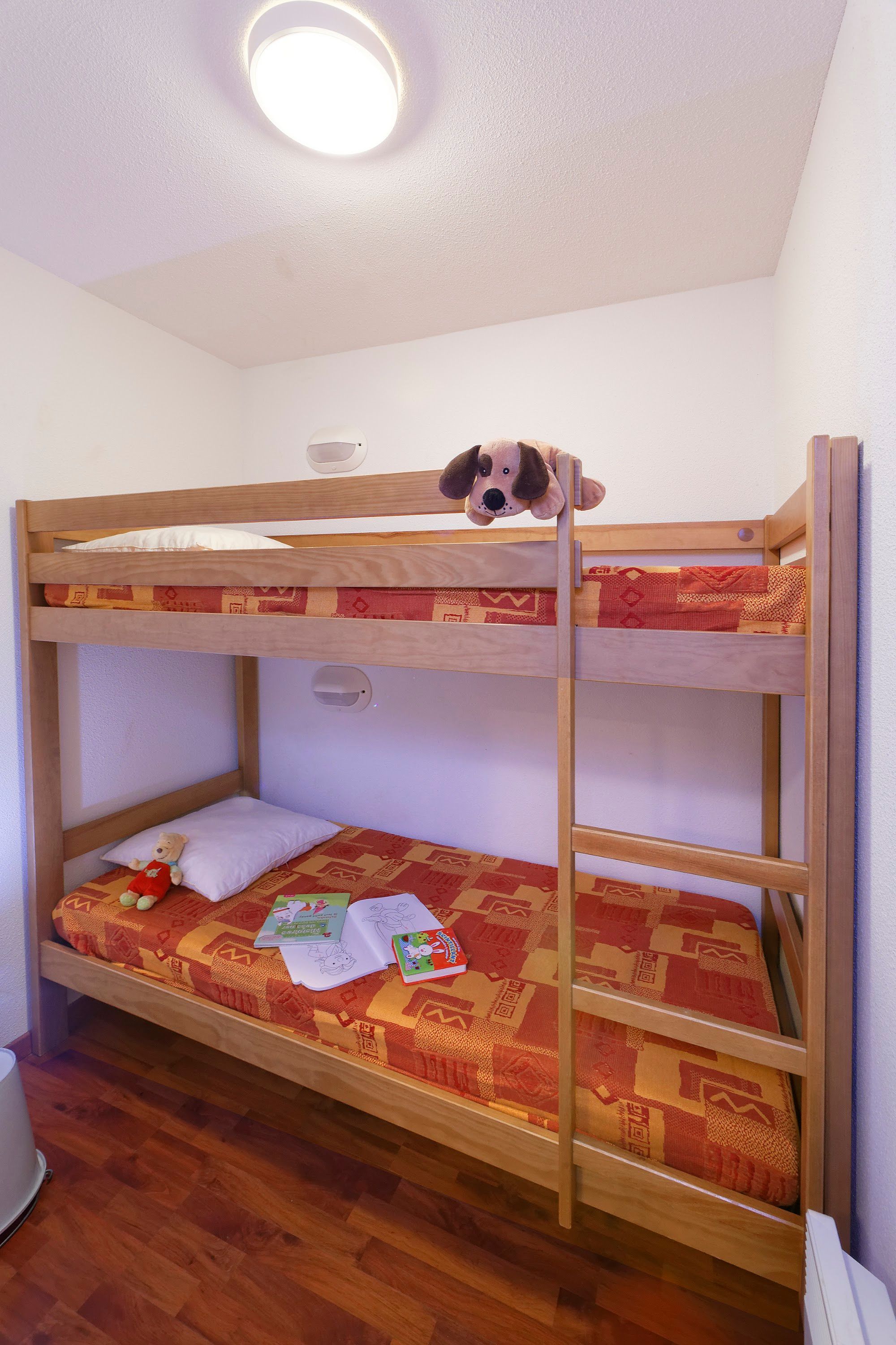 Un lit superposé avec un jouet pour chien sur le lit du haut et un ours en peluche sur le lit du bas.
