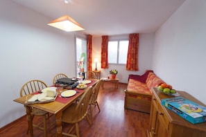 Un espace repas comprenant une table en bois, des chaises, un barbecue et un canapé.