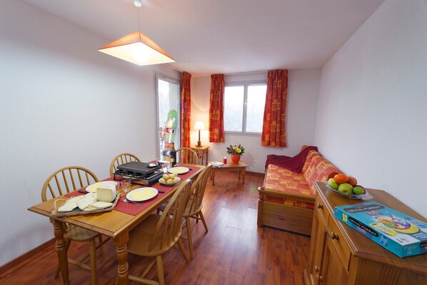 A dining area with a wooden table, chairs, a grill, and a sofa.