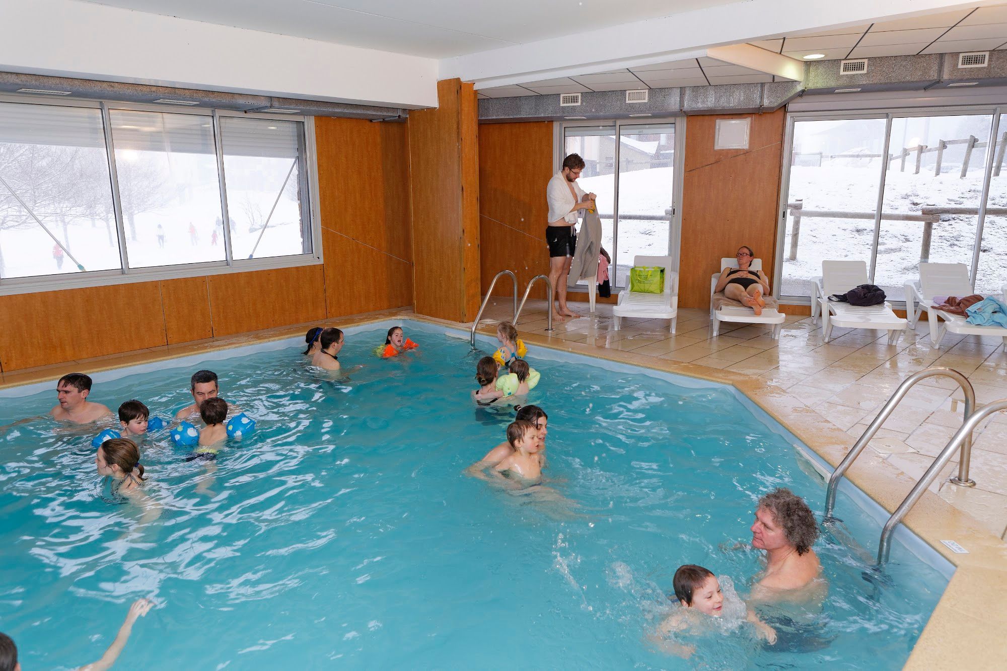 Une piscine intérieure où plusieurs personnes nagent et se détendent.