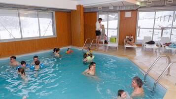 Une piscine intérieure où plusieurs personnes nagent et se détendent.