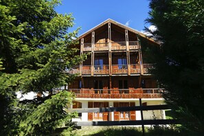 A multi-story wooden building with balconies, surrounded by trees. - À 50m des pistes et du centre | Piscine Chauffée (La Toussuire)