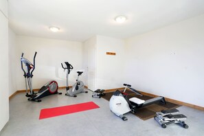 A fitness room with exercise equipment including a stationary bike, elliptical, treadmill, and a red exercise mat. - À 50m des pistes et du centre | Piscine Chauffée (La Toussuire)