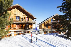 Un chalet en bois doté d’un balcon, entouré de neige et d’arbres.