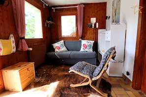 A cozy room with a sofa, a rocking chair, a wooden chest, and a window with curtains. - Apartment with large terrace and stunning views of the MatterhornOutside: apartment located on the g (St-Luc)