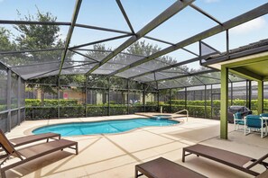 An outdoor pool area with a glass enclosure, lounge chairs, and a hot tub. - Spacious 5-bedroom house in lovely Davenport with AC (Davenport)