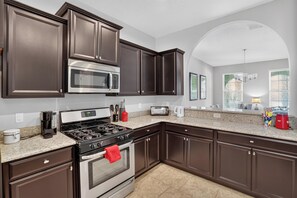 Una cocina moderna con armarios oscuros, electrodomésticos de acero inoxidable y encimera de granito.