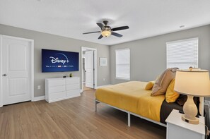 A bedroom with a bed, a ceiling fan, a television on the wall, and a window with blinds. - Spacious 5-bedroom house in lovely Davenport with AC (Davenport)