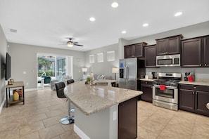 A modern kitchen with granite countertops, stainless steel appliances, and dark cabinetry. - Spacious 5-bedroom house in lovely Davenport with AC (Davenport)