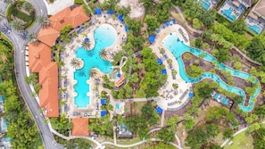 An aerial view of a resort with multiple swimming pools, palm trees, and a winding water slide. - Spacious 5-bedroom house in lovely Davenport with AC (Davenport)