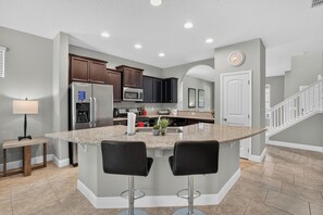 A modern kitchen with granite countertops, stainless steel appliances, and dark wood cabinets. - Spacious 5-bedroom house in lovely Davenport with AC (Davenport)