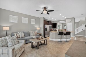 A modern living room with a sofa, coffee table, and a ceiling fan. - Spacious 5-bedroom house in lovely Davenport with AC (Davenport)
