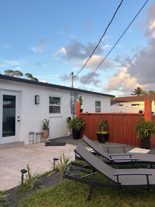 A residential property with a white exterior, a red fence, and outdoor seating. - 5 Bed - 3 Full Bath - pool home - 10 mins to beach (Pompano Beach)