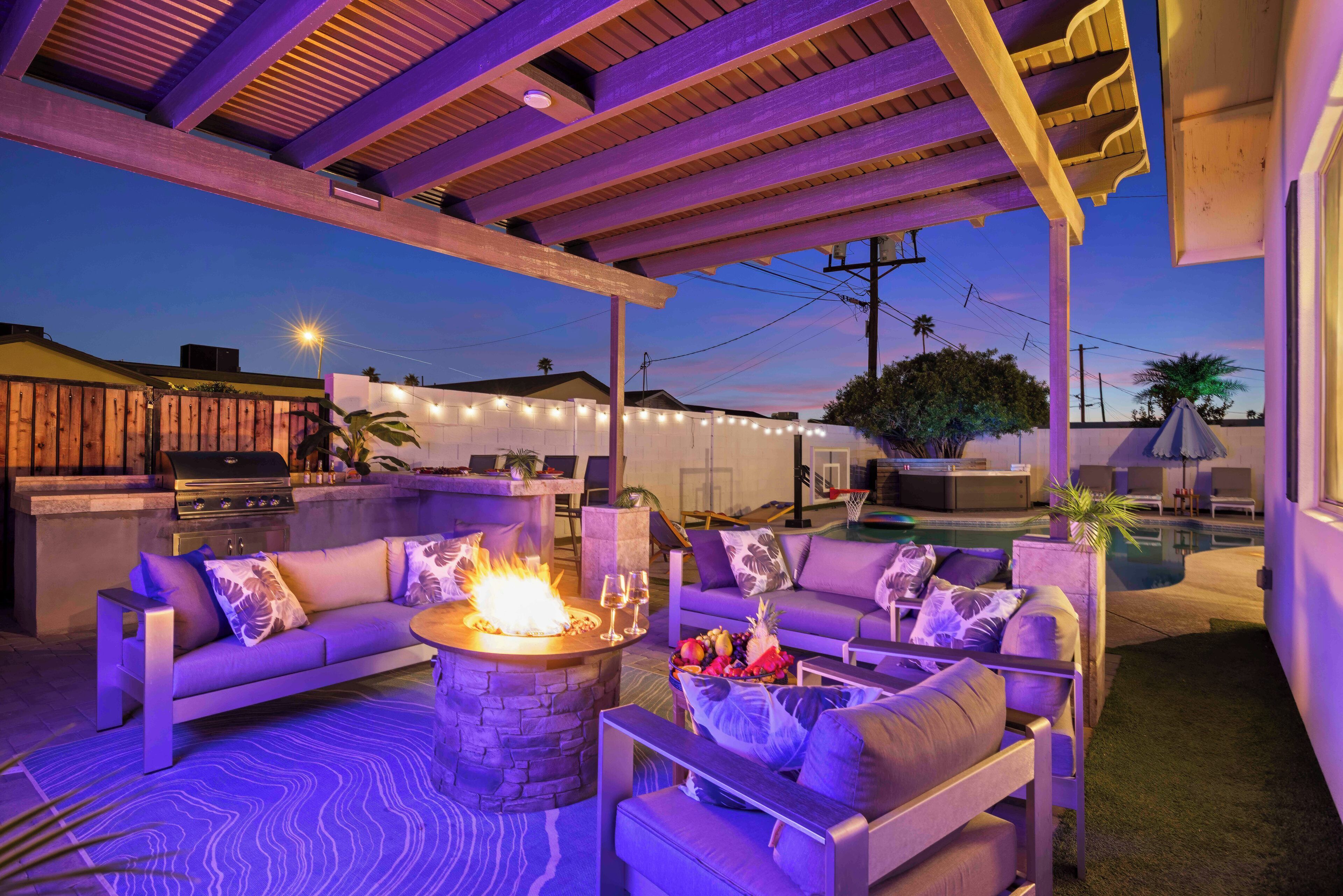An outdoor patio area with a fire pit, seating, and a pool.