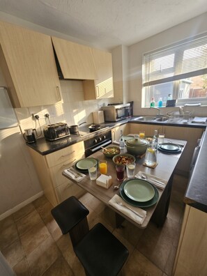 A modern kitchen with a dining area, equipped with a stove, microwave, and a large window providing natural light.
