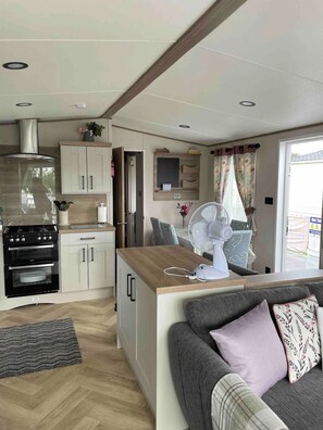 A compact kitchen with a built-in oven, a fan, and a wooden counter. - Charming Tattershall Mobile Home 3 Bedrooms, Private Entrance, Shared Pool (Lincoln)