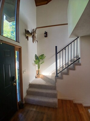 A staircase with a handrail, a potted plant, and a wall-mounted light fixture.