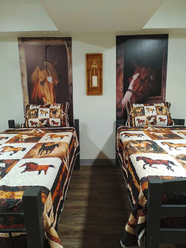 A bedroom with two beds, each with a horse-themed quilt and pillow.