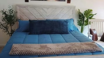 Un lit avec une tête de lit à motifs chevrons, une literie bleue et un coussin décoratif.