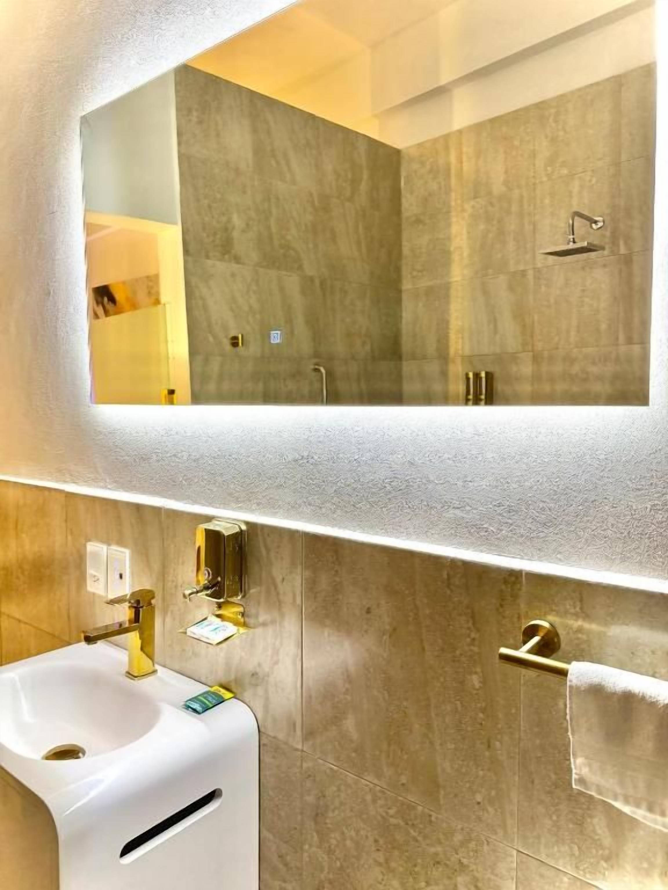Un baño con un espejo grande, un lavabo y un perchero para toallas.