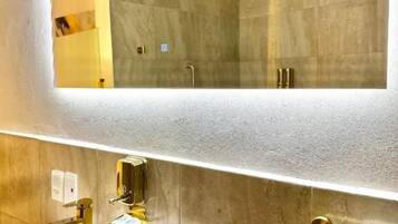 Un baño con un espejo grande, un lavabo y un perchero para toallas.