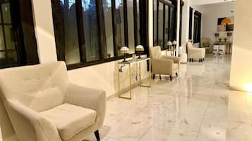 Amplia habitación con un ventanal grande, un sofá y una mesa con lámparas.