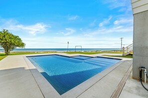 Ein rechteckiger Swimmingpool mit glasklarer blauer Wasseroberfläche, umgeben von einer Betonplattform.