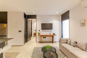 Ein modernes Wohnzimmer mit einer Couch, einem Couchtisch und einem an der Wand befestigten Fernseher.