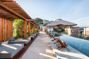 A rooftop pool area with lounge chairs and umbrellas, overlooking a cityscape. - Nice Apartment romantic zone close to the beach (Puerto Vallarta)