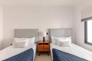 Ein Hotelzimmer mit zwei Betten, einem Nachttisch und einem Fenster.