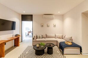 Ein modernes Wohnzimmer mit Sofa, Couchtisch und Fernseher.