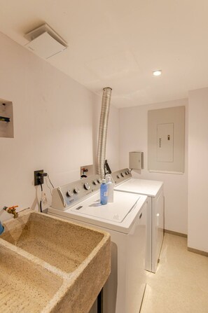 A laundry room with two washing machines, a sink, and a ventilation duct. - Nice Apartment romantic zone close to the beach (Puerto Vallarta)