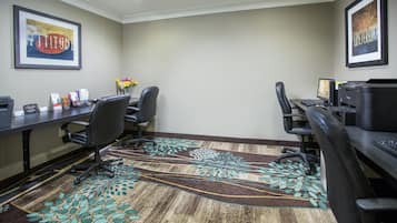 A conference room with two desks, chairs, computers, and a carpet with a leaf pattern.