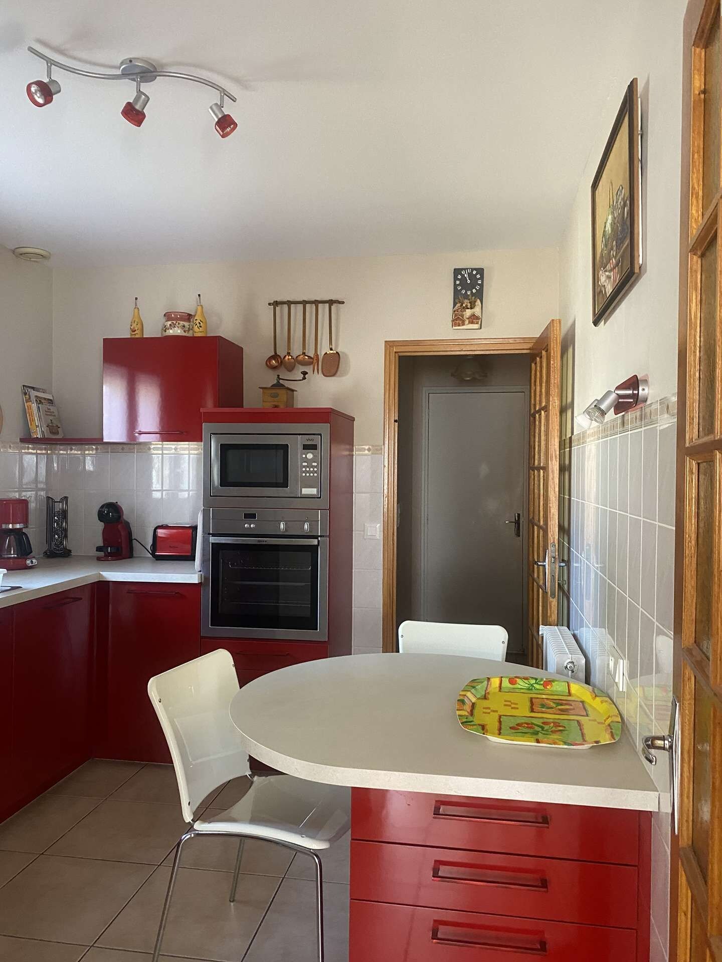 Una cucina compatta con forno a microonde, forno e mobili rossi.