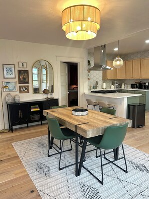 Een moderne keuken met een eethoek, met een houten tafel, groene stoelen en een hanglamp.