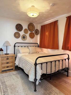 Een slaapkamer met een bed, nachtkastje, lamp en decoratie aan de muur.