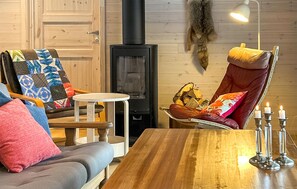 A cozy room with a wooden table, two chairs, a small round table, a fireplace, and a lamp.