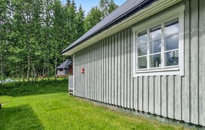 A single-story building with a large window on the right side, surrounded by a grassy yard and trees. - Pet friendly home in Ljungdalen with sauna (Ljungdalen)